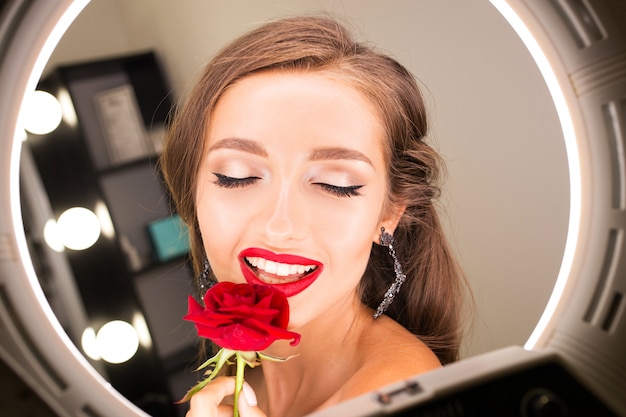 Retrato de una hermosa niña con labios rojos y una rosa