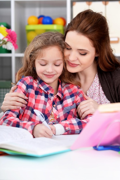 Retrato de una hermosa niña linda con madre haciendo la tarea