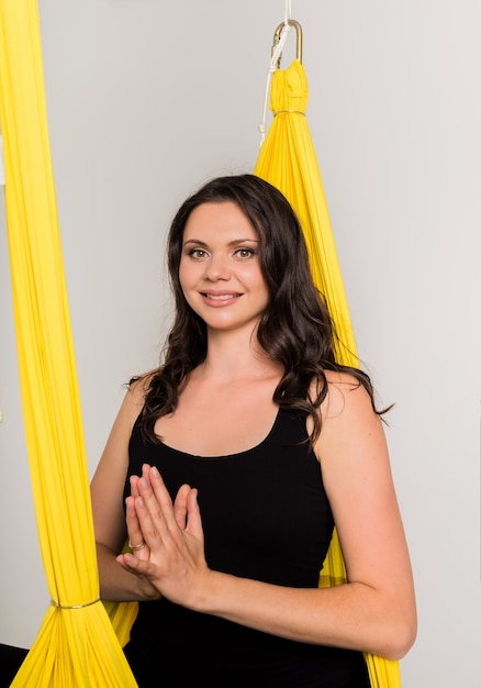 Retrato de una hermosa niña con las manos juntas en Namaste sobre una pared blanca