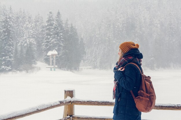 Retrato de una hermosa niña con una mochila sobre un fondo de bosque nevado.