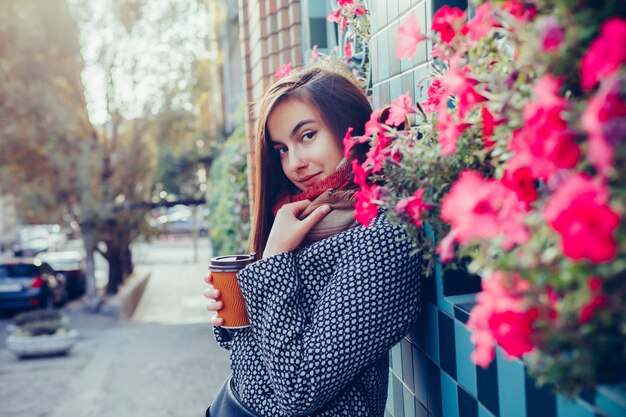 Retrato de hermosa niña morena con bebida para llevar en la calle