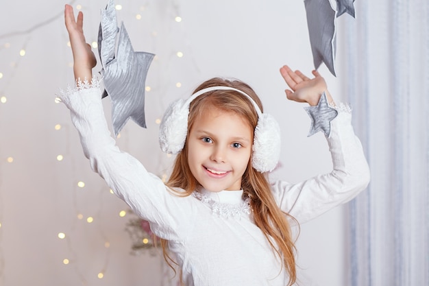 Retrato de una hermosa niña con orejeras en el interior con adornos navideños