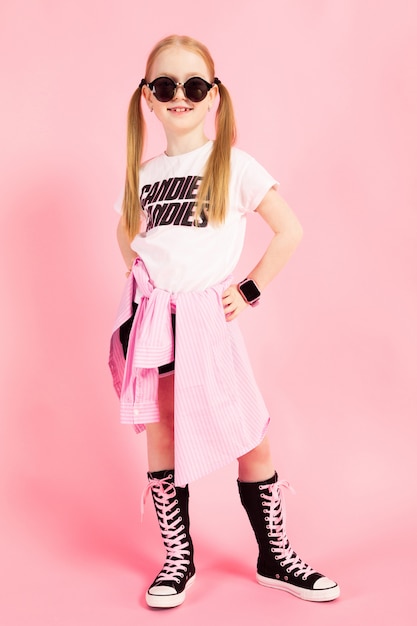 Foto retrato de una hermosa niña en pantalones cortos, una camiseta y zapatillas altas.