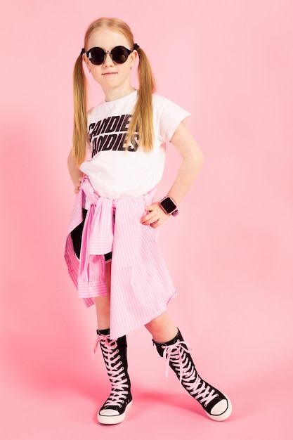 Retrato de una hermosa niña en pantalones cortos, una camiseta y zapatillas altas.