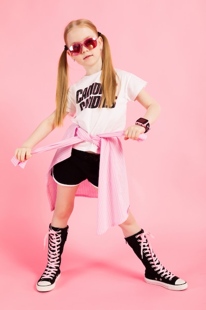 Retrato de una hermosa niña en pantalones cortos, una camiseta y zapatillas altas.