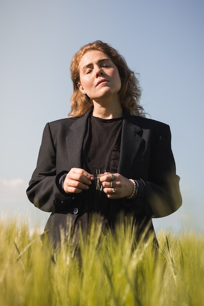 Retrato de una hermosa niña con el pelo rojo en un campo. La niña está vestida con un traje de hombre. Verano, campo, naturaleza.