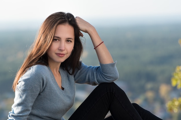 Retrato de una hermosa niña pensativa al aire libre. Bosque en la distancia, día soleado