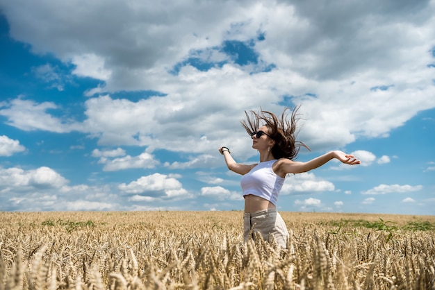 Retrato de una hermosa niña posando en el campo de trigo disfrutando del horario de verano. libertad