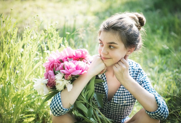 Retrato de una hermosa niña con un ramo de peonías.