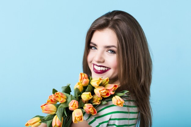 Retrato de una hermosa niña con un ramo de tulipanes.