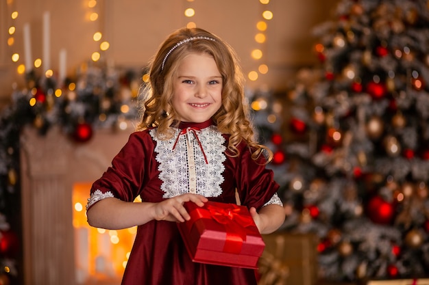 Retrato de una hermosa niña con un regalo rojo