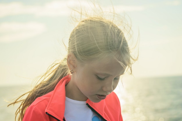 Retrato de una hermosa niña con sol brillante junto al mar.