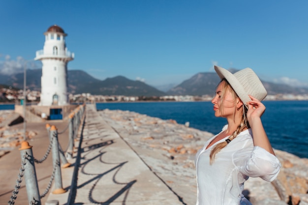 Retrato de una hermosa niña con sombrero y camisa blanca cerca del faro