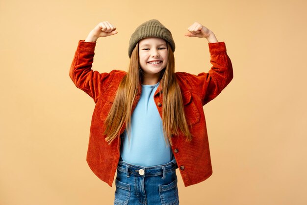 Retrato de una hermosa niña sonriente con un elegante sombrero verde que muestra los músculos del bíceps