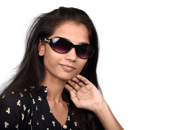 Retrato de una hermosa niña sonriente en gafas de sol en blanco