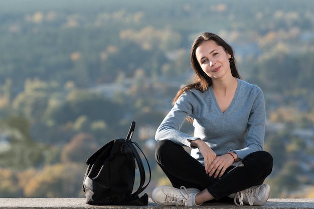 Retrato de una hermosa niña sonriente con una mochila al aire libre. Día soleado