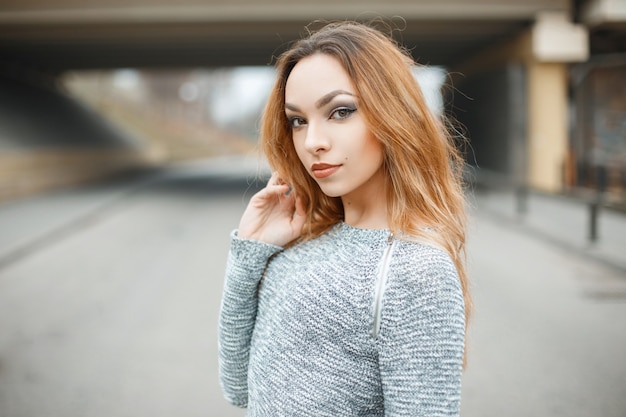 Retrato de una hermosa niña con un suéter en la calle