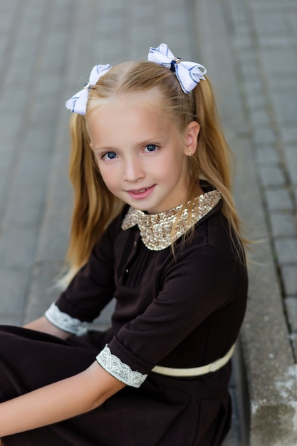 Retrato de una hermosa niña en uniforme escolar antes de la clase en la escuela