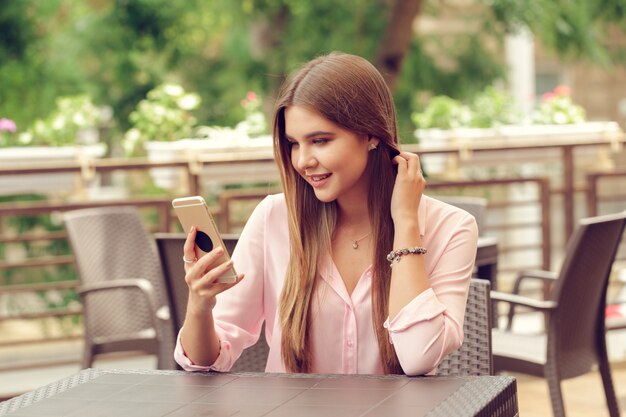 Retrato de hermosa niña usando su teléfono móvil en la cafetería