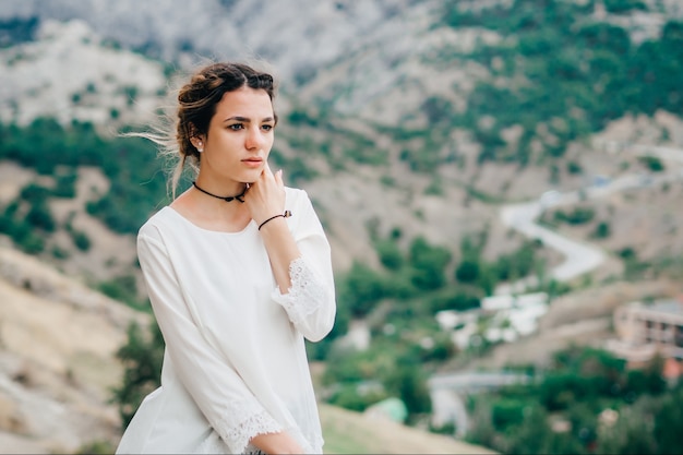 Retrato de una hermosa niña viajera de pie en las montañas