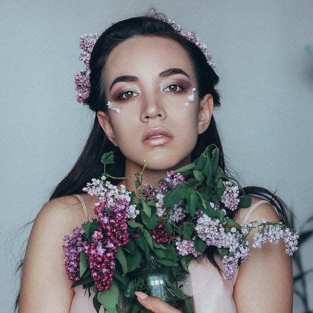 Retrato de una hermosa novia con flores contra la pared