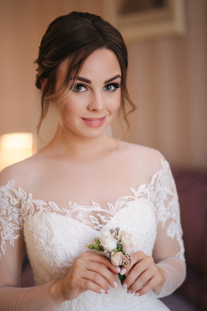 Retrato de hermosa novia en hotel. El día de la boda, la mujer sostiene la flor y espera al novio.