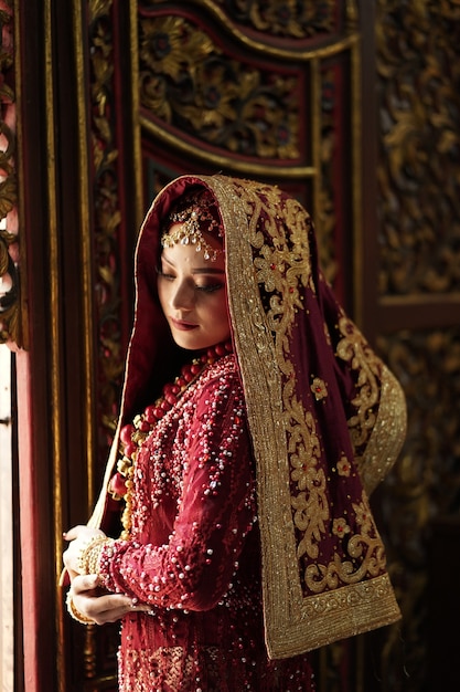 Retrato de una hermosa novia india en vestido rojo y dorado