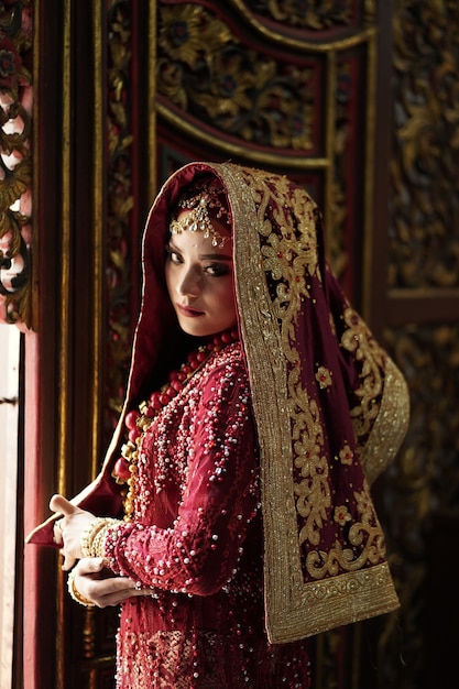 Retrato de una hermosa novia india en vestido rojo y dorado