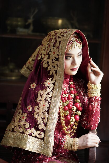 Retrato de una hermosa novia india en vestido rojo y dorado