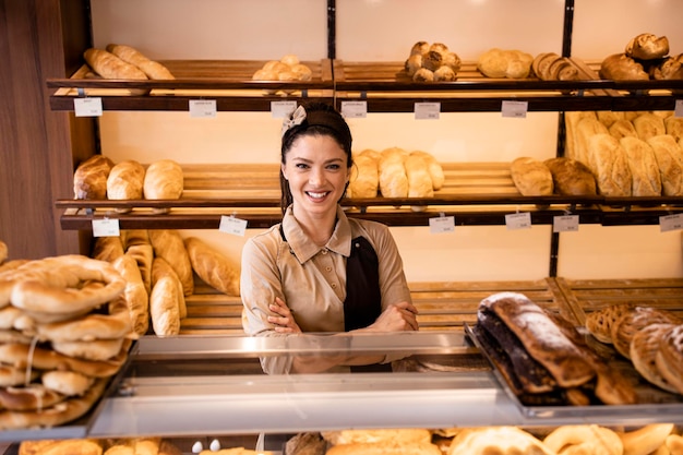 Retrato de una hermosa panadera con los brazos cruzados en una panadería