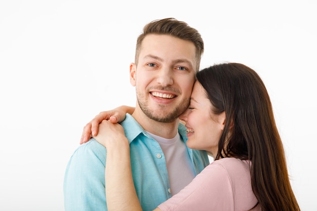 Retrato de una hermosa pareja amada Un chico y una chica se abrazan y miran a la cámara sonriendo Sobre un fondo blanco