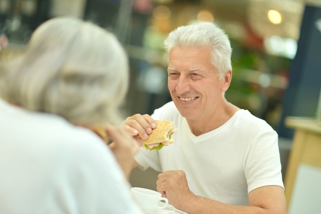 Retrato de hermosa pareja de ancianos comiendo comida rápida