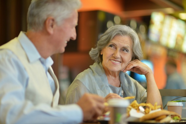 Retrato de hermosa pareja de ancianos comiendo comida rápida