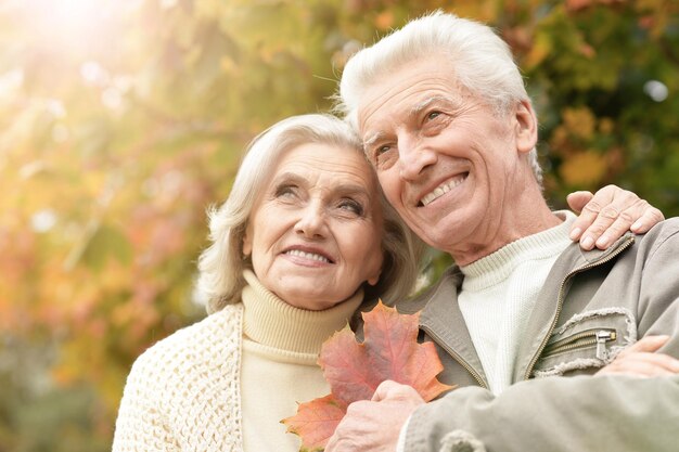 retrato de una hermosa pareja de mayores con hojas en el parque
