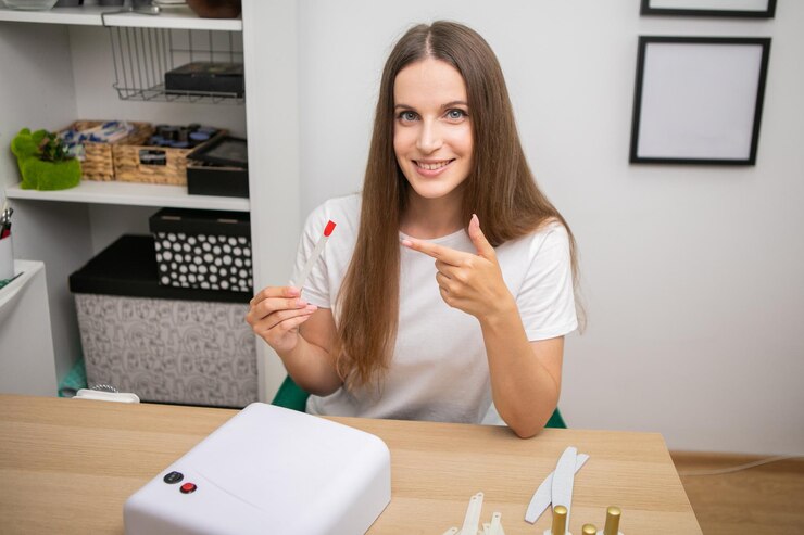 Retrato de una hermosa y sonriente clienta que muestra el color de las coloridas puntas de las uñas
