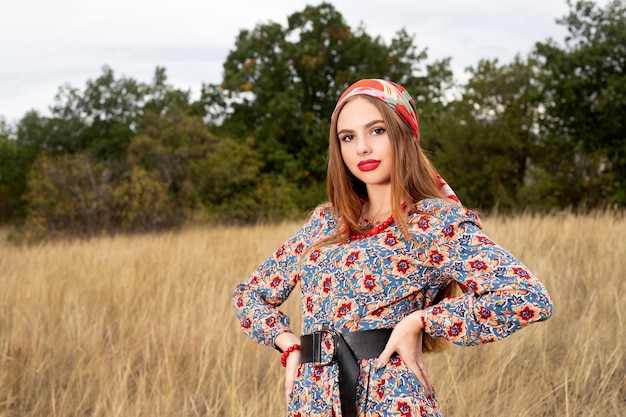 Retrato de una hermosa y sonriente niña en una bufanda y perlas rojas en la naturaleza