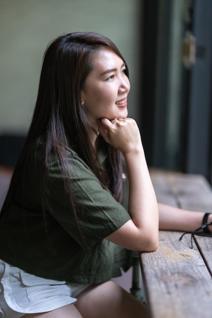 Un retrato de una hermosa viajera asiática feliz con un vestido verde pardusco elegante estilo de vida soleado de verano en una cafetería como el fondo