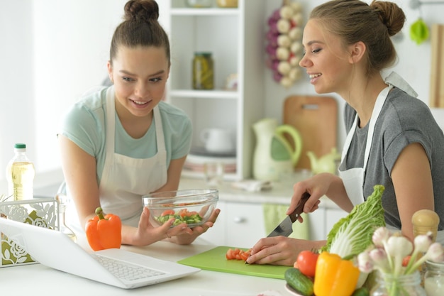 Retrato de hermosas adolescentes haciendo ensalada en la cocina