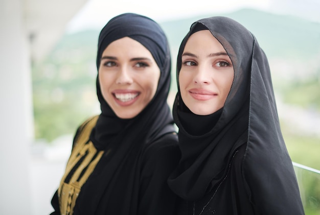 retrato de hermosas mujeres musulmanas vestidas a la moda con hijab de pie en un balcón que representa la moda islámica moderna y el concepto de ramadán kareem