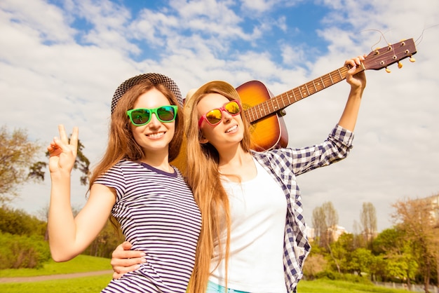 Retrato de hermosas mujeres en vasos con guitarra en el parque