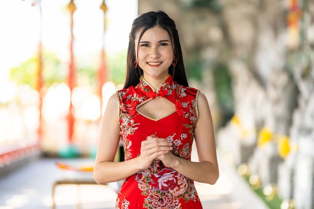 Retrato de hermosas sonrisas joven asiática vistiendo rojo cheongsam chino tradicional, para el Festival del Año Nuevo Chino en el santuario chino