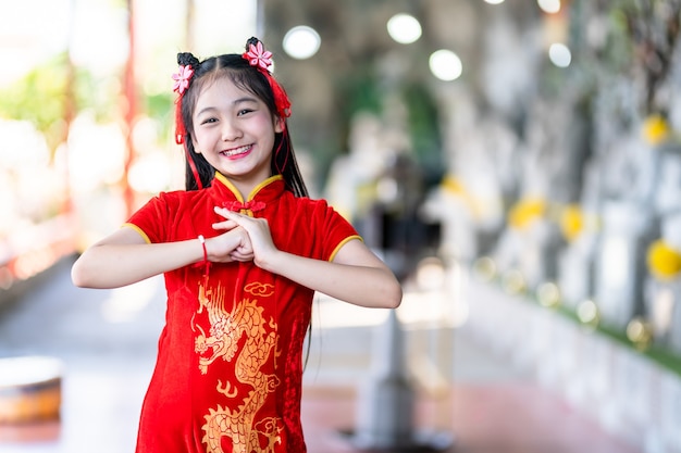Retrato hermosas sonrisas Linda niña asiática vistiendo rojo cheongsam chino tradicional, para el Festival del Año Nuevo Chino en el santuario chino
