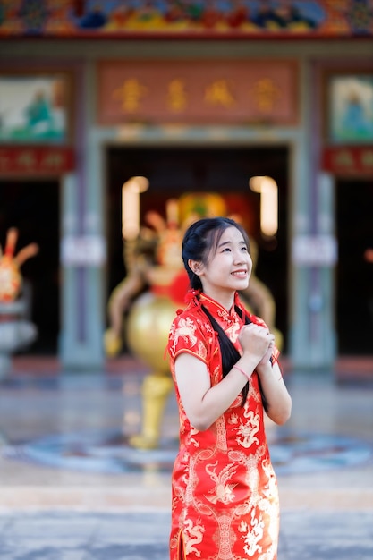 Retrato hermosas sonrisas lindas mujer joven asiática con decoración de cheongsam chino tradicional rojo y sosteniendo un Fanning chino para el Festival de Año Nuevo Chino en el santuario chino en Tailandia