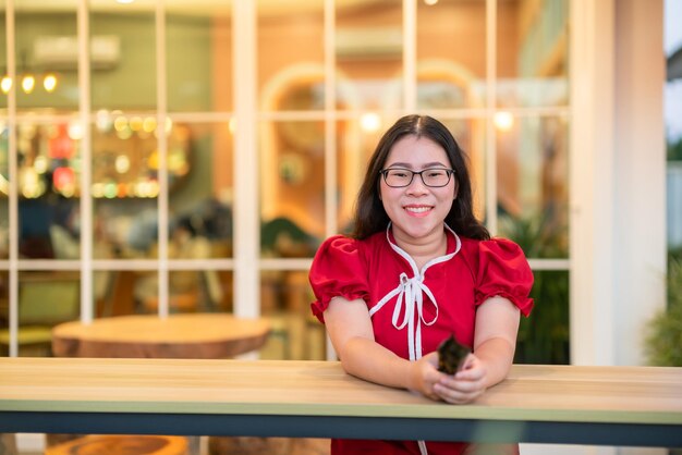 Retrato hermosas sonrisas mujer joven asiática vestida con decoración china tradicional roja y sosteniendo un Fanning chino para el Festival de Año Nuevo Chino en el café restaurante chino