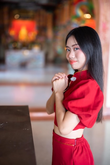 Retrato hermosas sonrisas Mujer joven asiática con vestido rojo cheongsam decoración tradicional para el festival de año nuevo chino celebrar la cultura de china en el santuario chino Lugares públicos en Tailandia