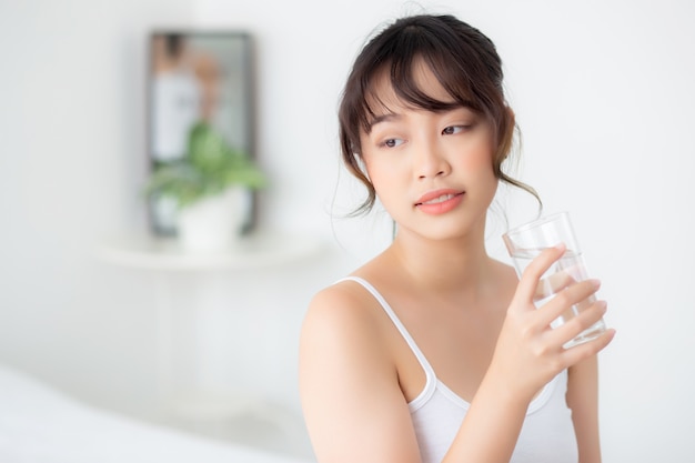 Retrato hermoso joven mujer asiática sonrisa y vaso de agua potable con fresco y puro para la dieta