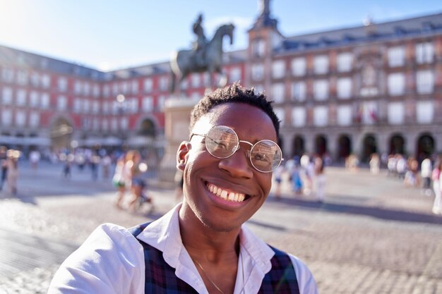 Retrato de un hermoso joven viajero con gafas caminando por Madrid en un día soleado en la ciudad