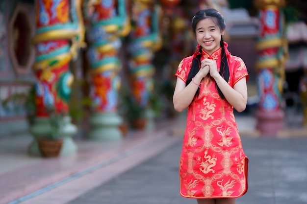 Retrato hermoso lindo sonrisas mujer joven asiática con vestido rojo cheongsam decoración tradicional