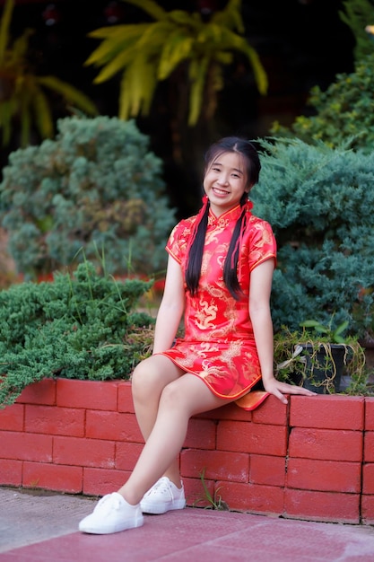 Retrato hermoso lindo sonrisas mujer joven asiática con vestido rojo cheongsam decoración tradicional