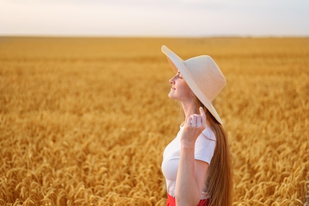 retrato, de, hermoso, mujer joven, en, sombrero, en, campo de trigo, plano de fondo, vista lateral